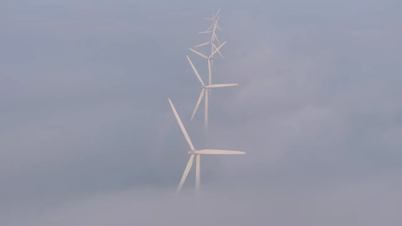 Windturbines spinning with low clouds at Friesland during sunrise aerial