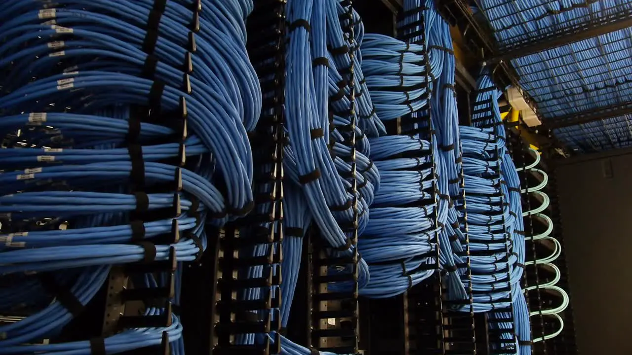 Dolly shot revealing a large network of blue cables intertwined in a server room