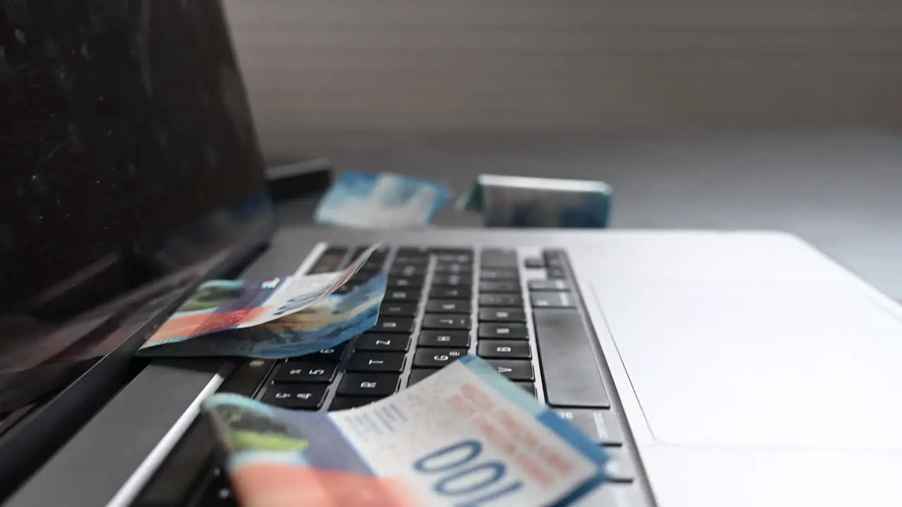 Side view of a laptop with bank notes laying on the keyboard online business brings cash