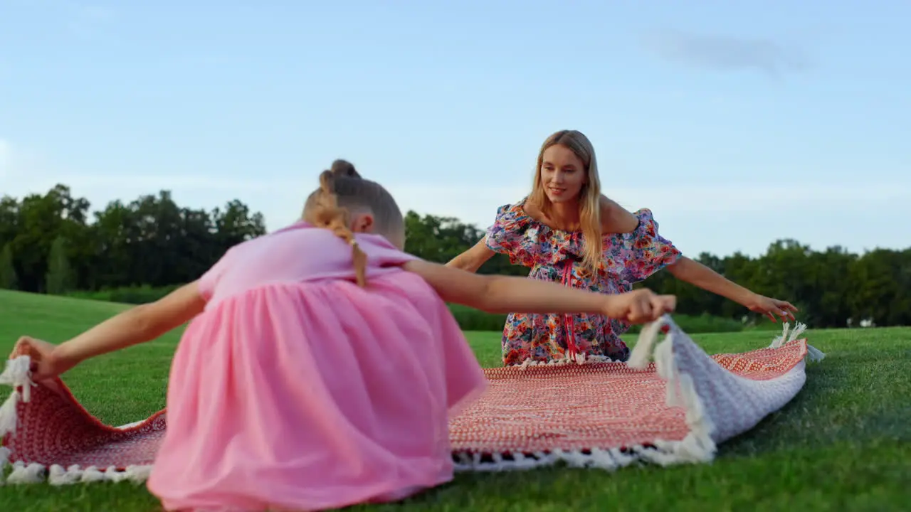 Joyful mother and daughter enjoying family weekend on green grass at meadow