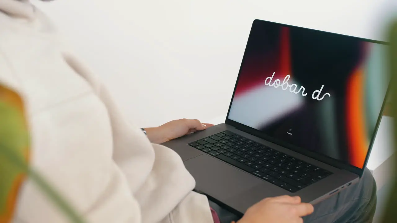 Person sit on couch at home opening new M1 MacBook Pro display