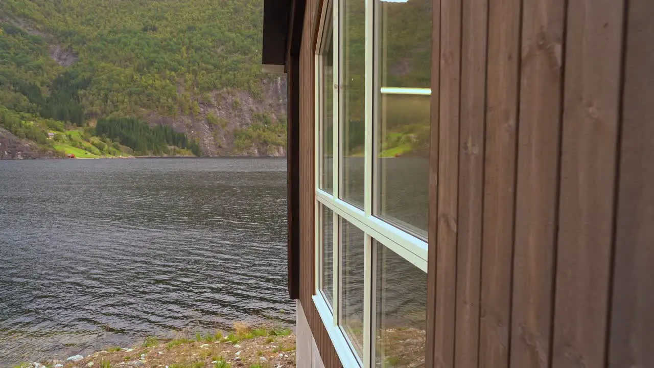 Camera sliding along wall of hydroelectric powerplant Markaani in Norway before revealing warning sign telling about powerplant Bolstadfjord sea in background