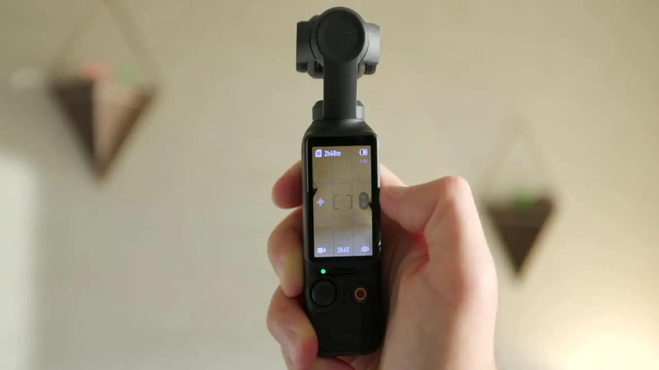 Close Up View Of DJI Osmo Pocket 3 Held In Hand And Screen Being Flipped From Vertical To Landscape Mode And Turning Gimbal Head