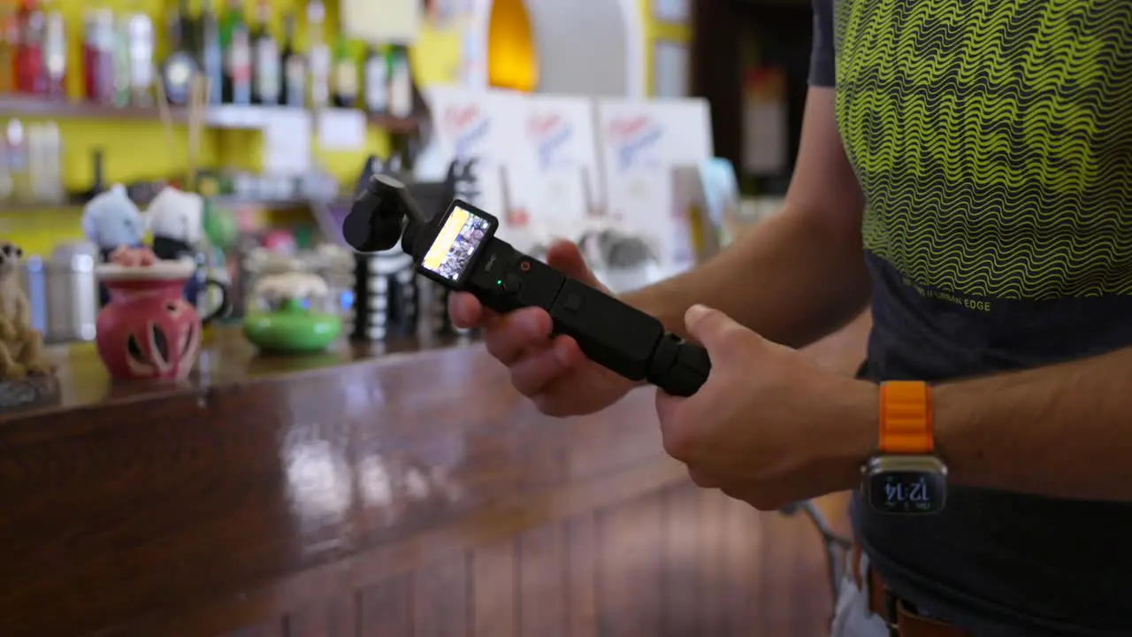 Content Creator Attaching Battery Handle And Mini Tripod Beside Cafe Bar