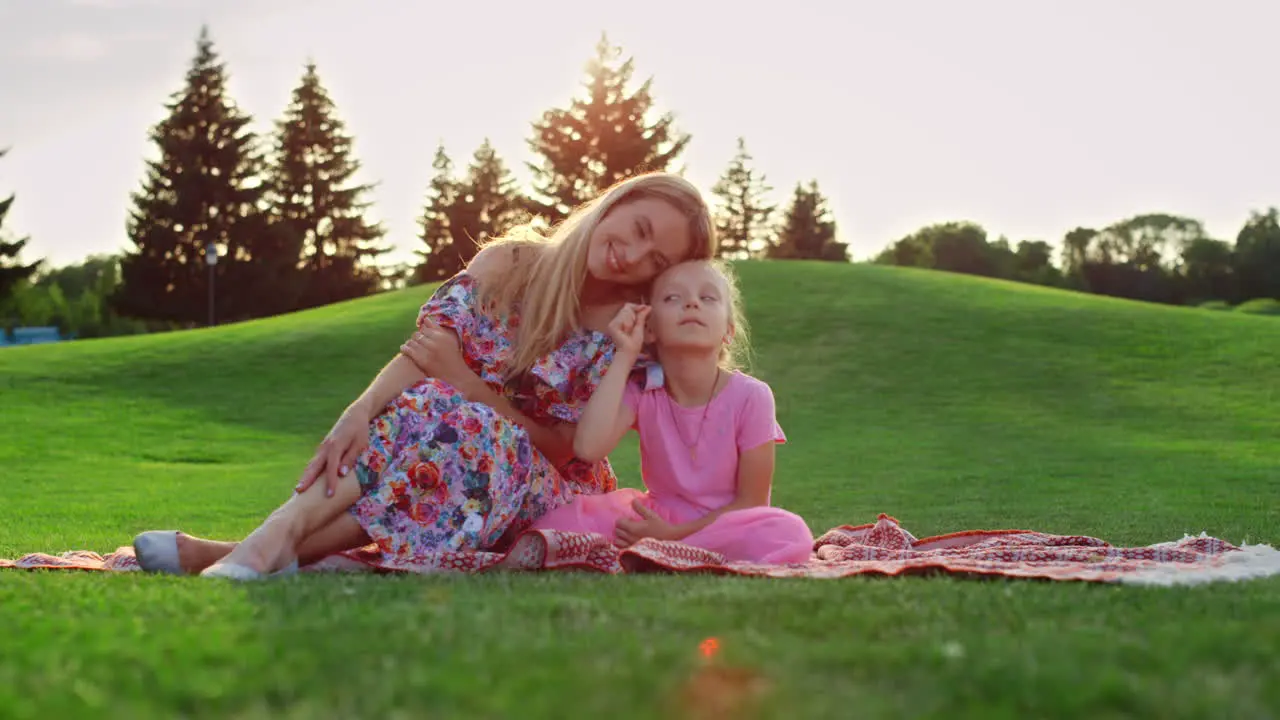 Family posing at sunset time at meadow Woman hugging girl in city park