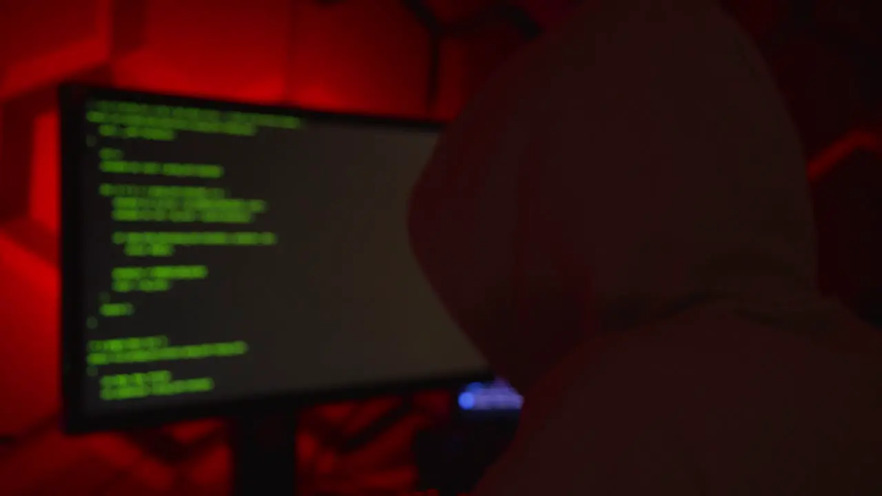 Anonymous hacker in a hoody writing code