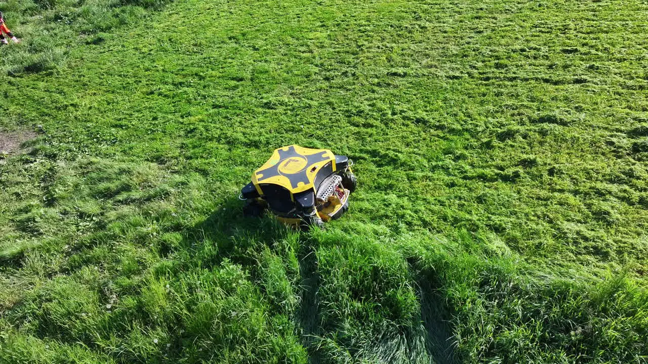 Drone Shot of Remotely Controlled Modern Lawn Mower in Green Grassland on Sunny Day