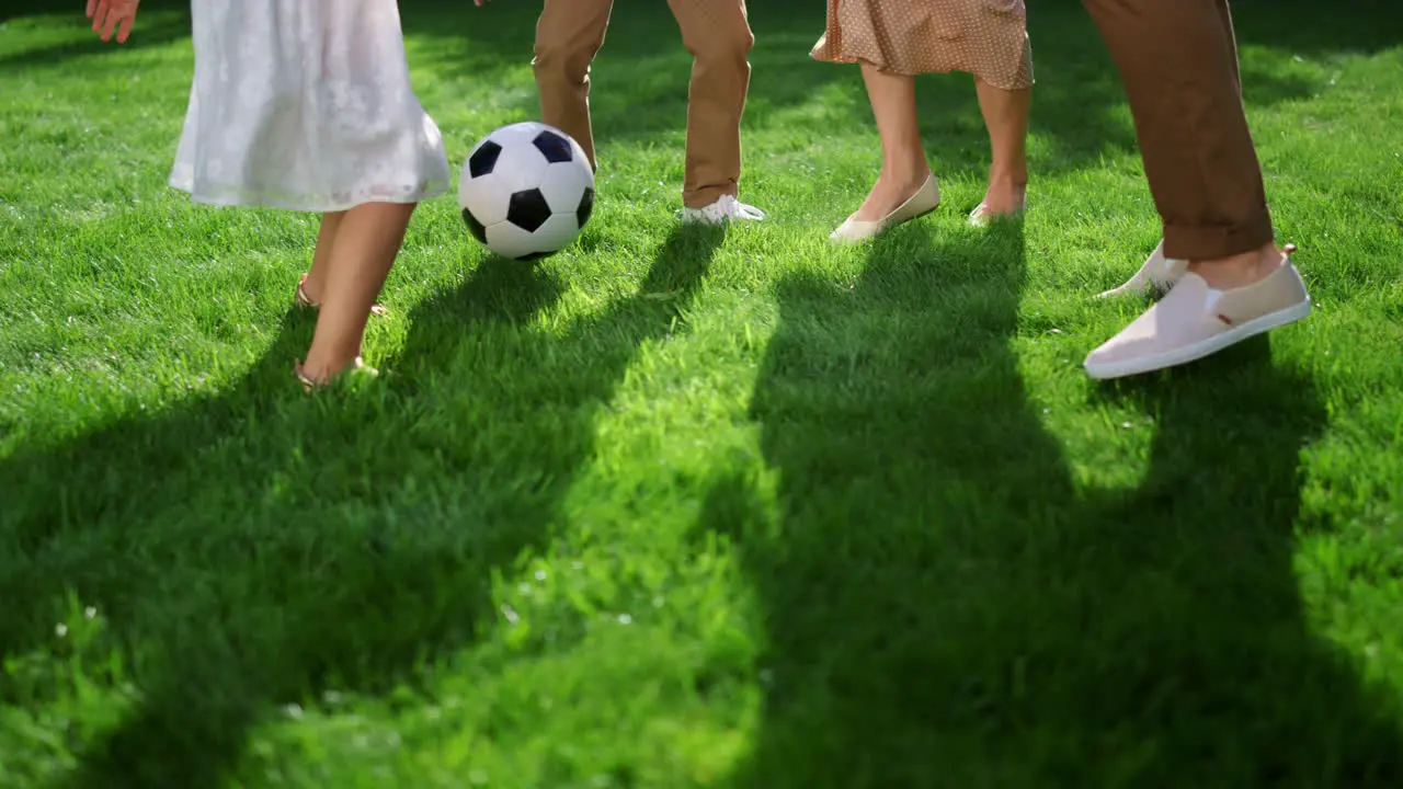 Closeup of parents and kids feet playing with soccer ball in green park