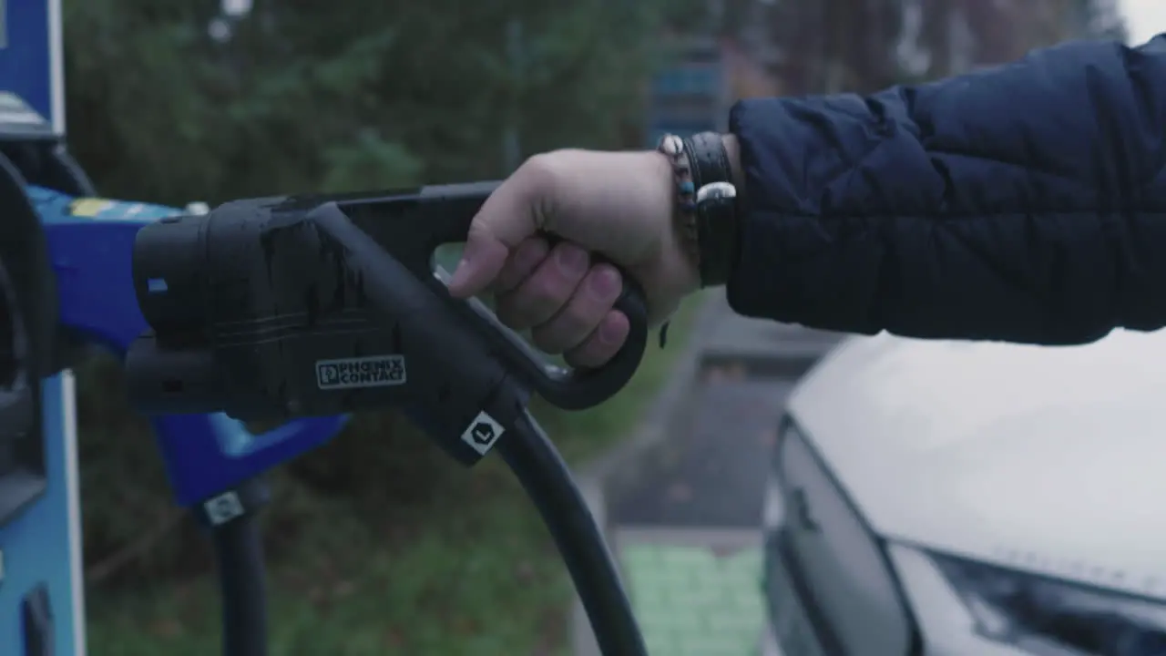 Hand Taking Plug on Charging Station For Electric Cars Close Up