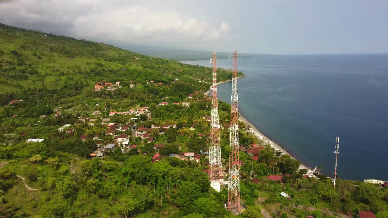 aerial 5g telecom tower couple pairs over a cliff with blu water ocean view and green jungle natural vegetation data wireless smartphone internet social media connection