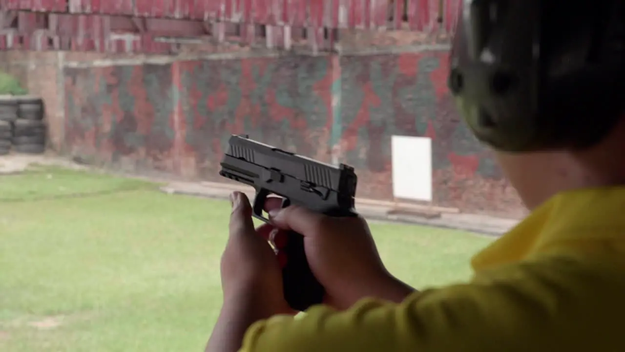 Slow motion scenes of The gun firing at a shooting range on the man hand withhold the gun tight and pull the trigger