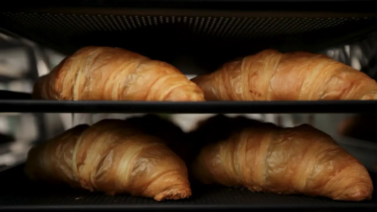 Golden croissants on bakery tray close-up with soft focus warm lighting gives a cozy bakery feel elevator shot