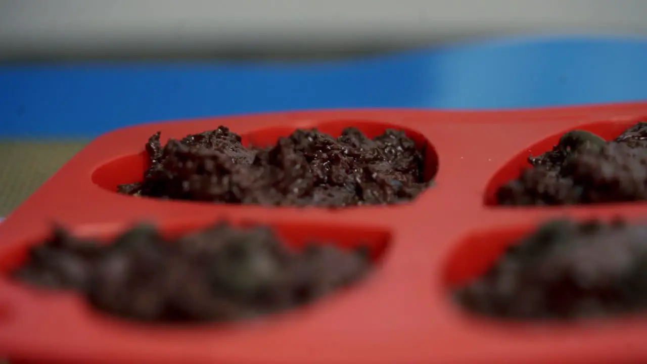 Close up adding chocolate chips to chocolate beets muffins inside of baking tray for valentines day candy heart love