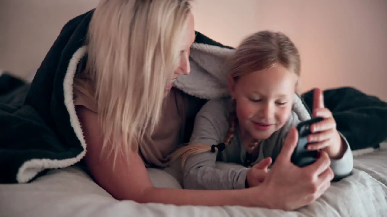 Mom daughter and smartphone in bedroom