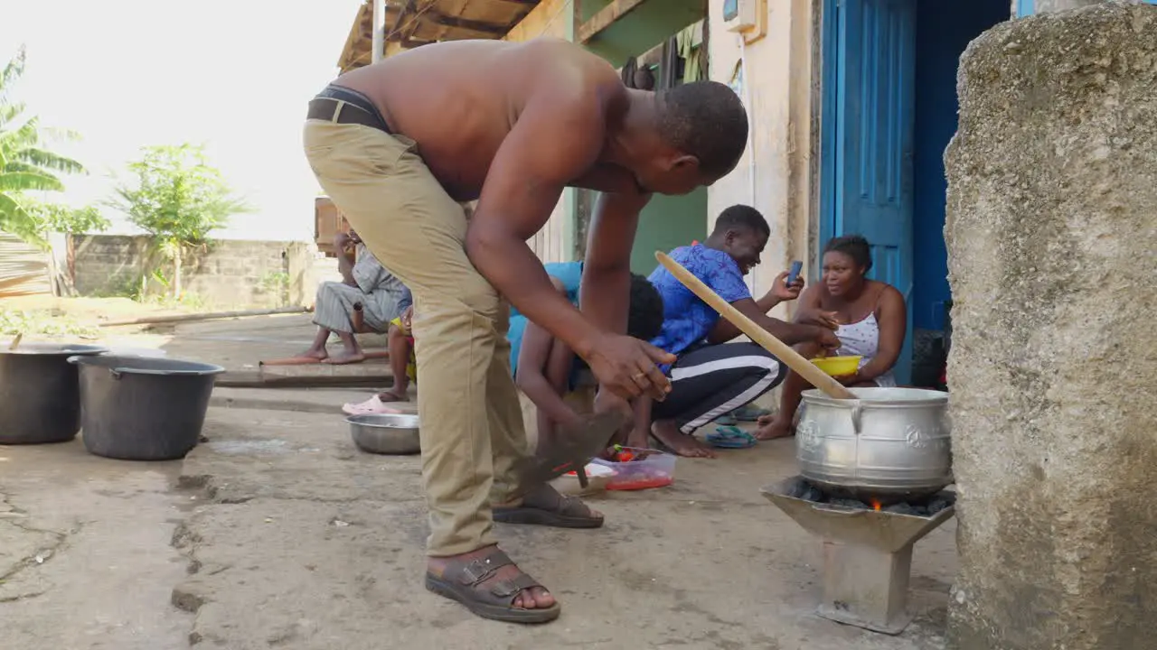 Man stirs the fire of the pot where Banku mixture of maize and cassava Ghanaian cuisine is cooked