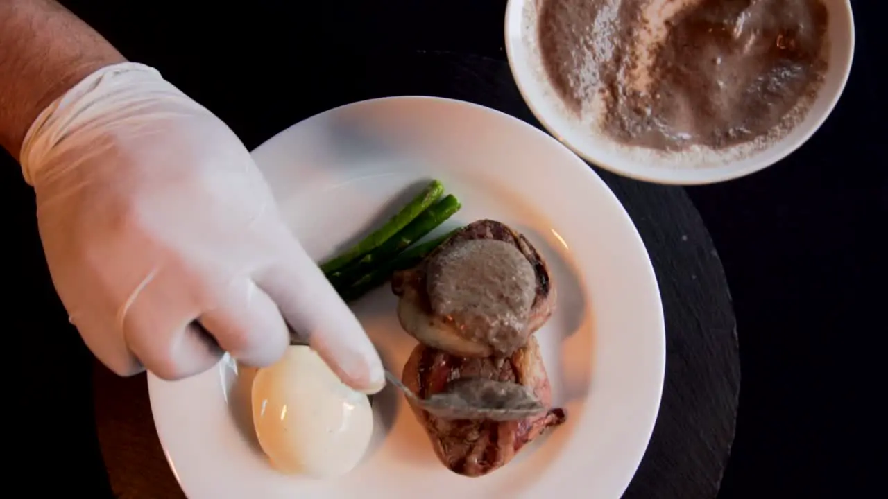 A hands of chef putting gravy in a filet mignon