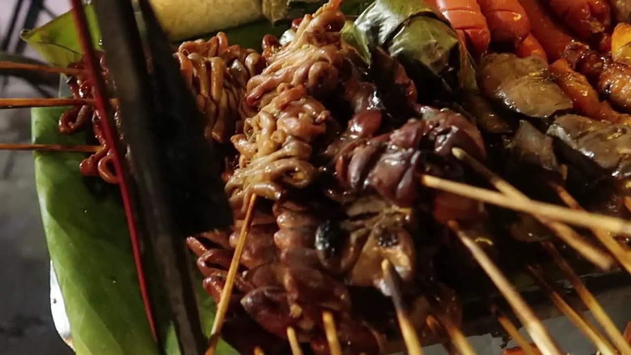 Diverse grilled meat in BBQ skewers on street food cart at thai night market