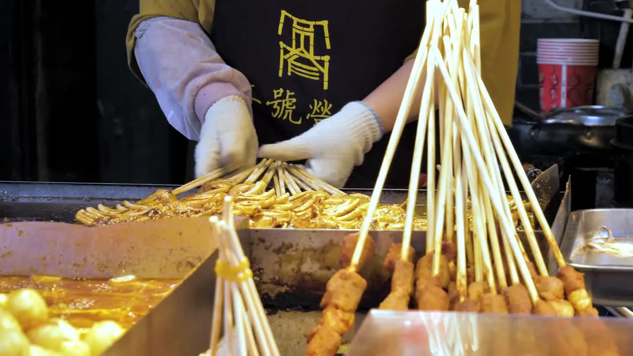 Street Food Person Cooking Squid Kebabs with With Gloves and Apron in Chengdu China