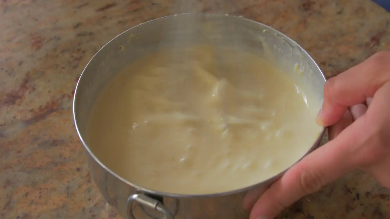 Close up of a hand mixing ingredients in a steel bowl with a whisk