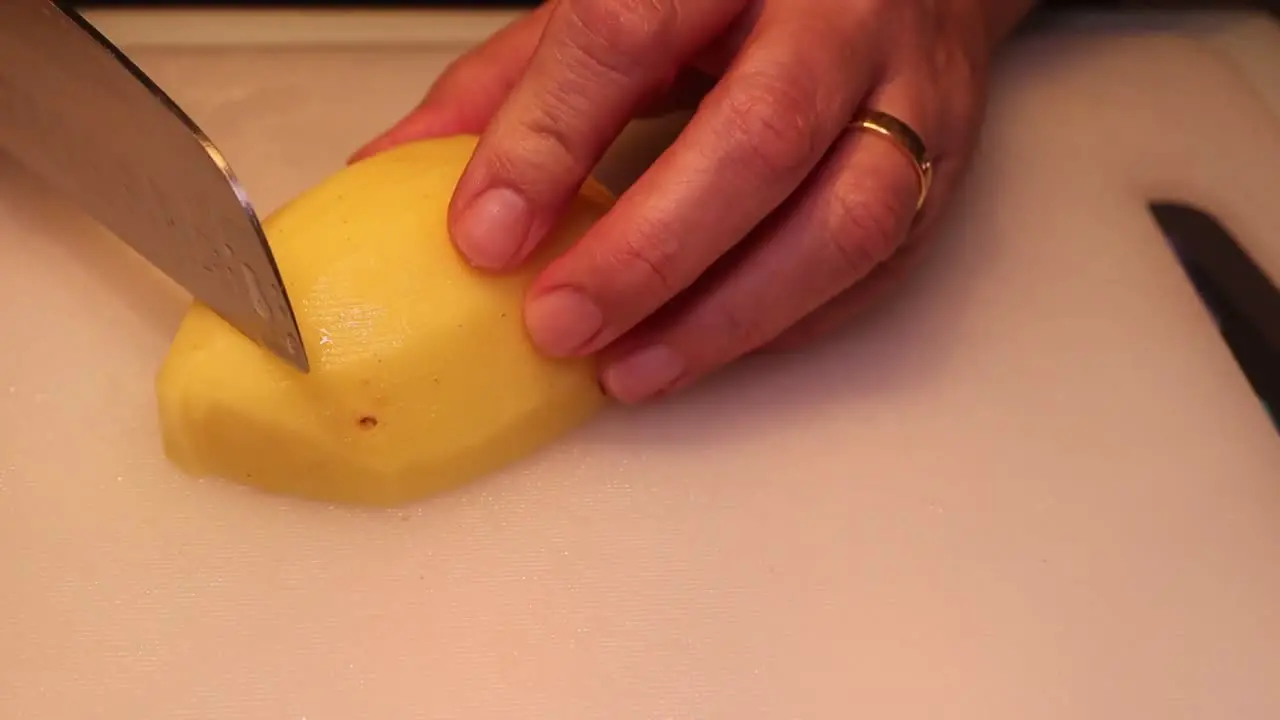 Woman cutting the potatoes on the board in the kitchen