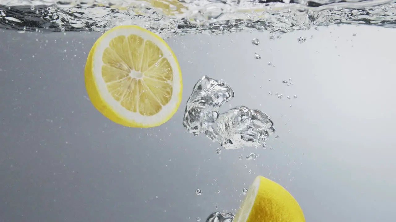 Two lemon halfs falling in clear fresh water