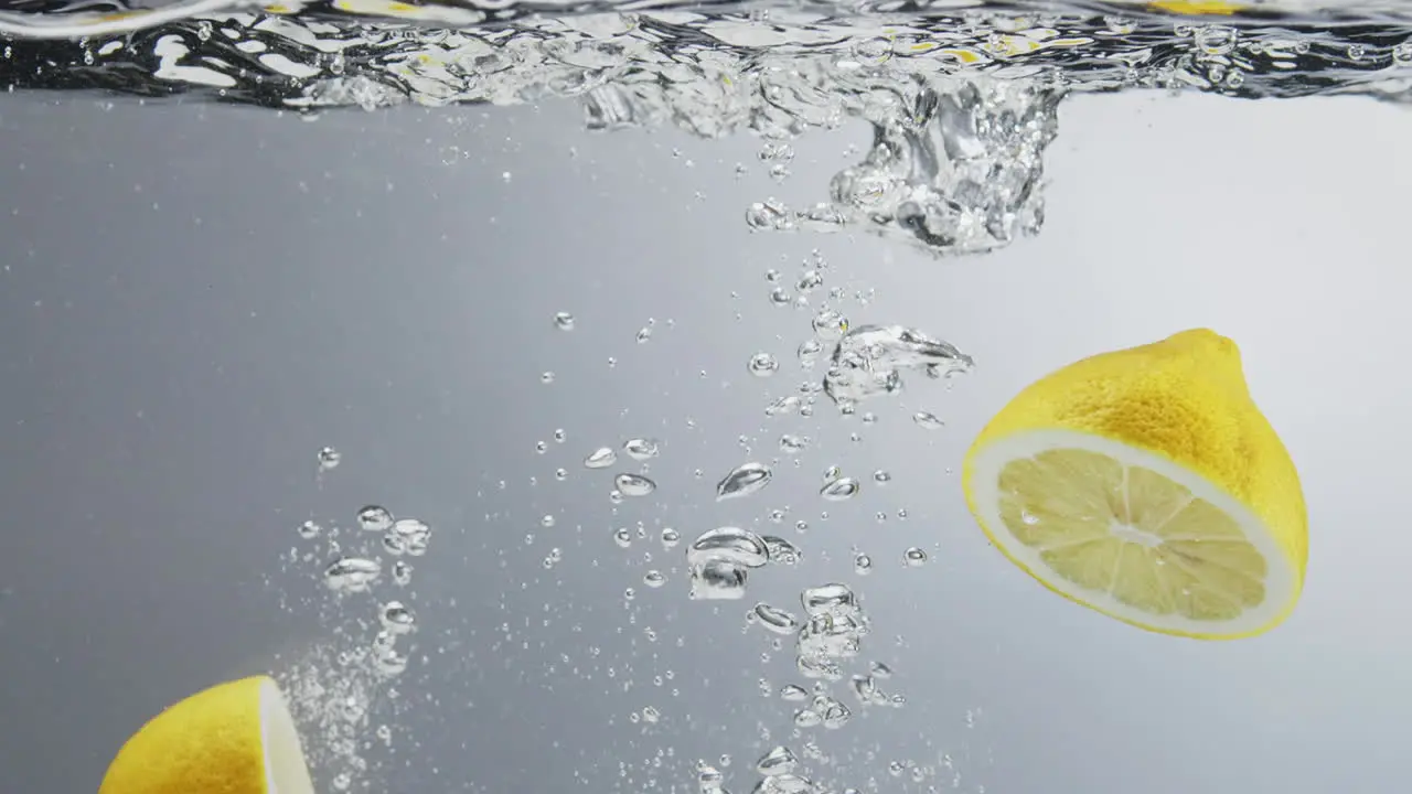 Underwater shot of lemon falling in water and splitting in halfs