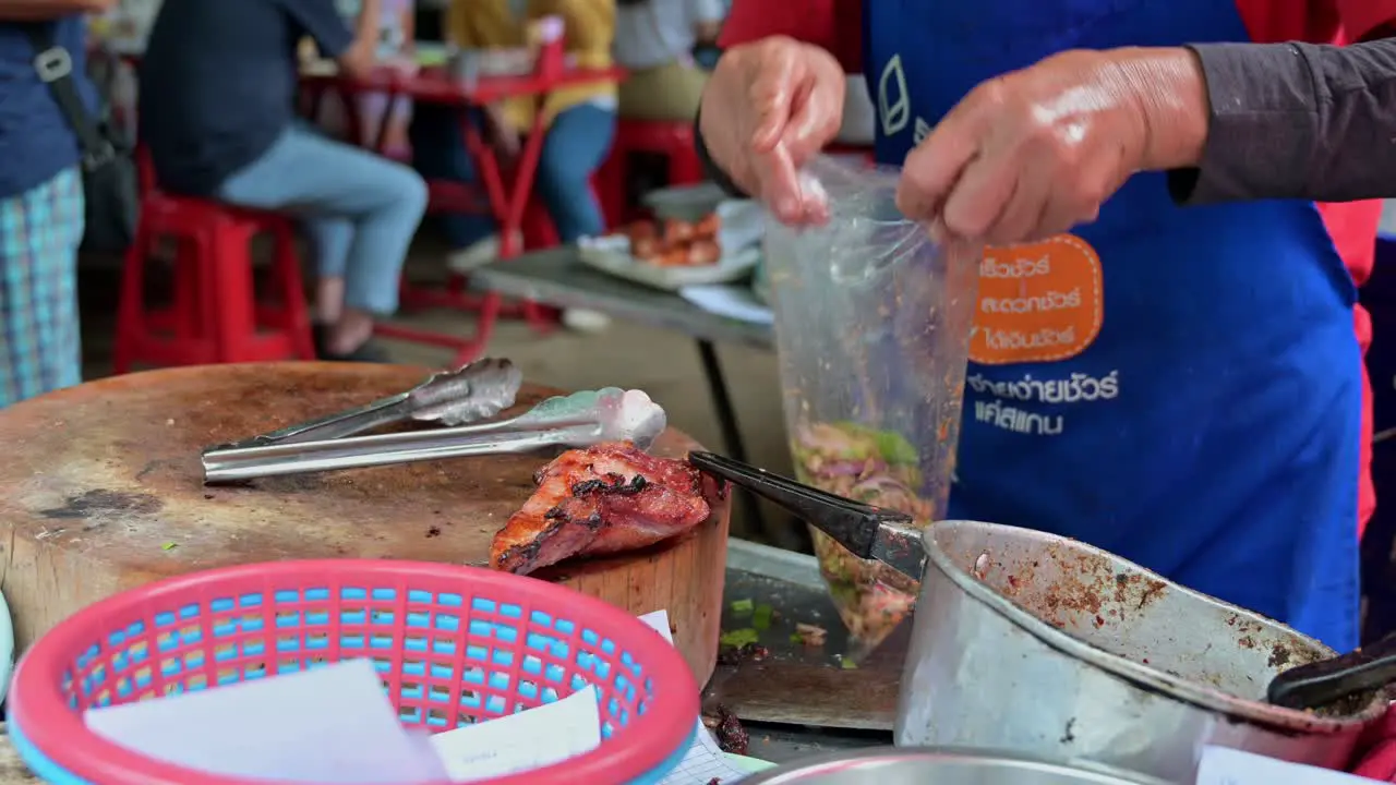 Traditional Northeastern Thai food called Laab with grilled pork prepared by a local cook in a roadside restaurant in the streets of Bangkok Thailand