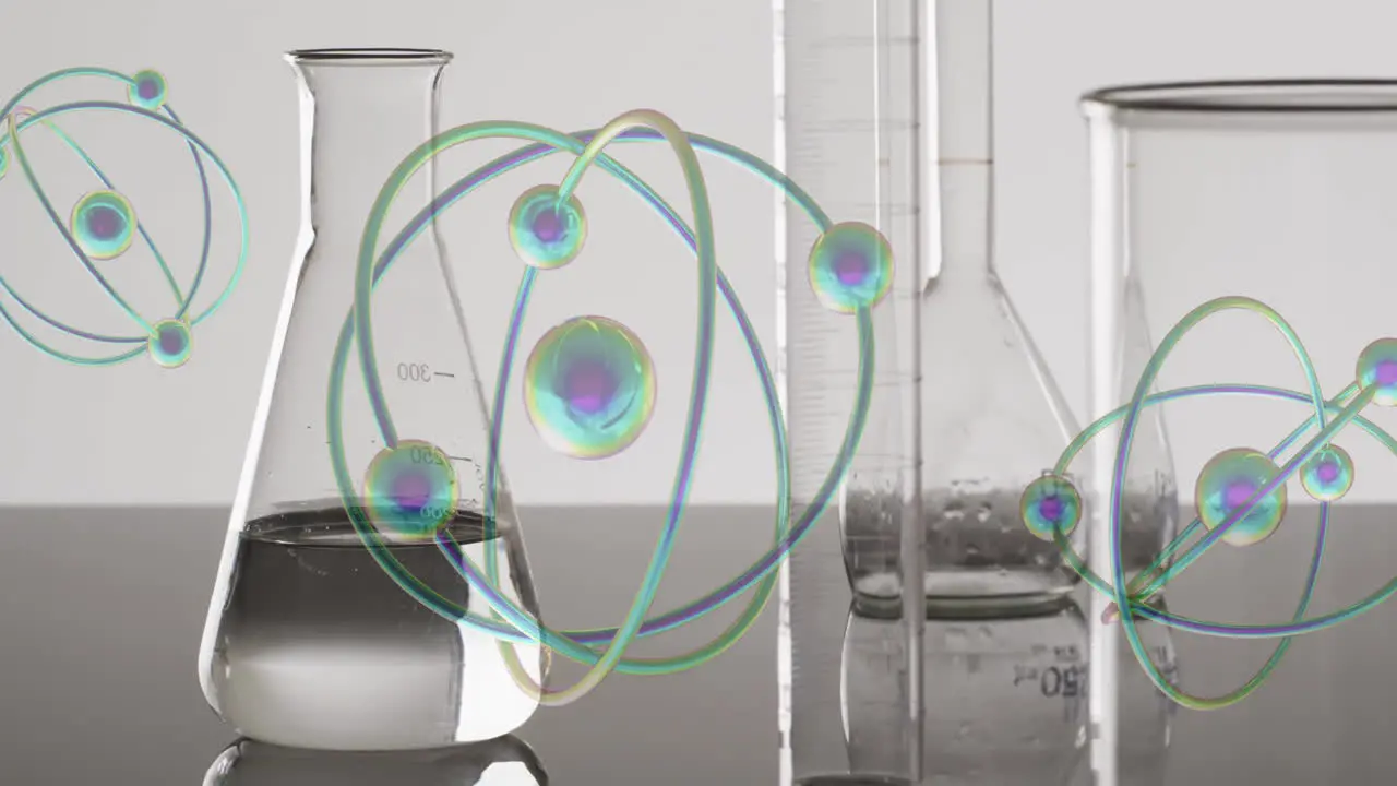 Animation of atoms moving over laboratory dishes on grey background