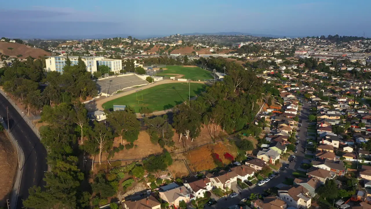 Flying over Beautiful Surburban Los Angeles Town Towards Epic High School with Green Football Field