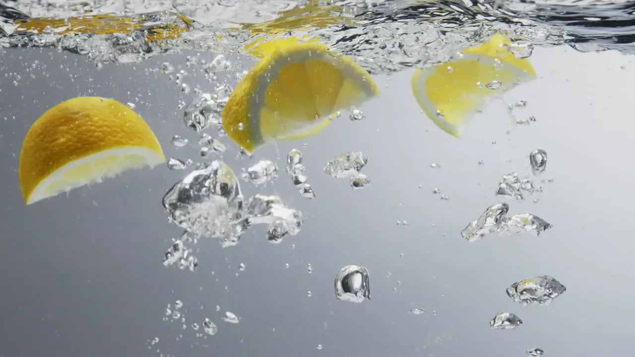 Lemon quarters falling into fresh clear water with bubbles