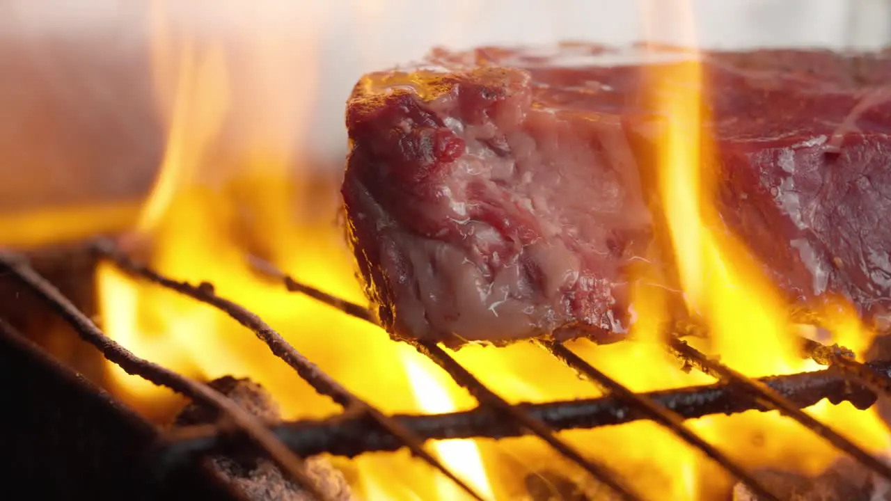 Close-up of grilled fillet steak between flames and embers of barbecue charcoal