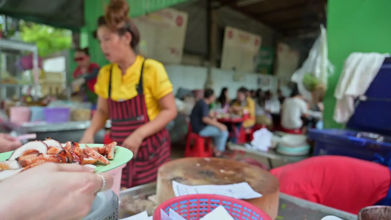 Busy street food vendors are getting orders and serving their customers in a roadside restaurant in the streets of Bangkok Thailand