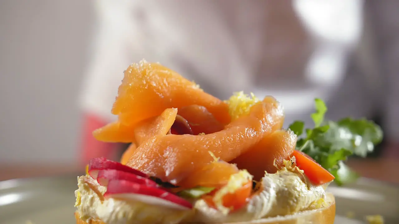 Close-up of lemon zest drops on a smoked salmon bagel with cream cheese