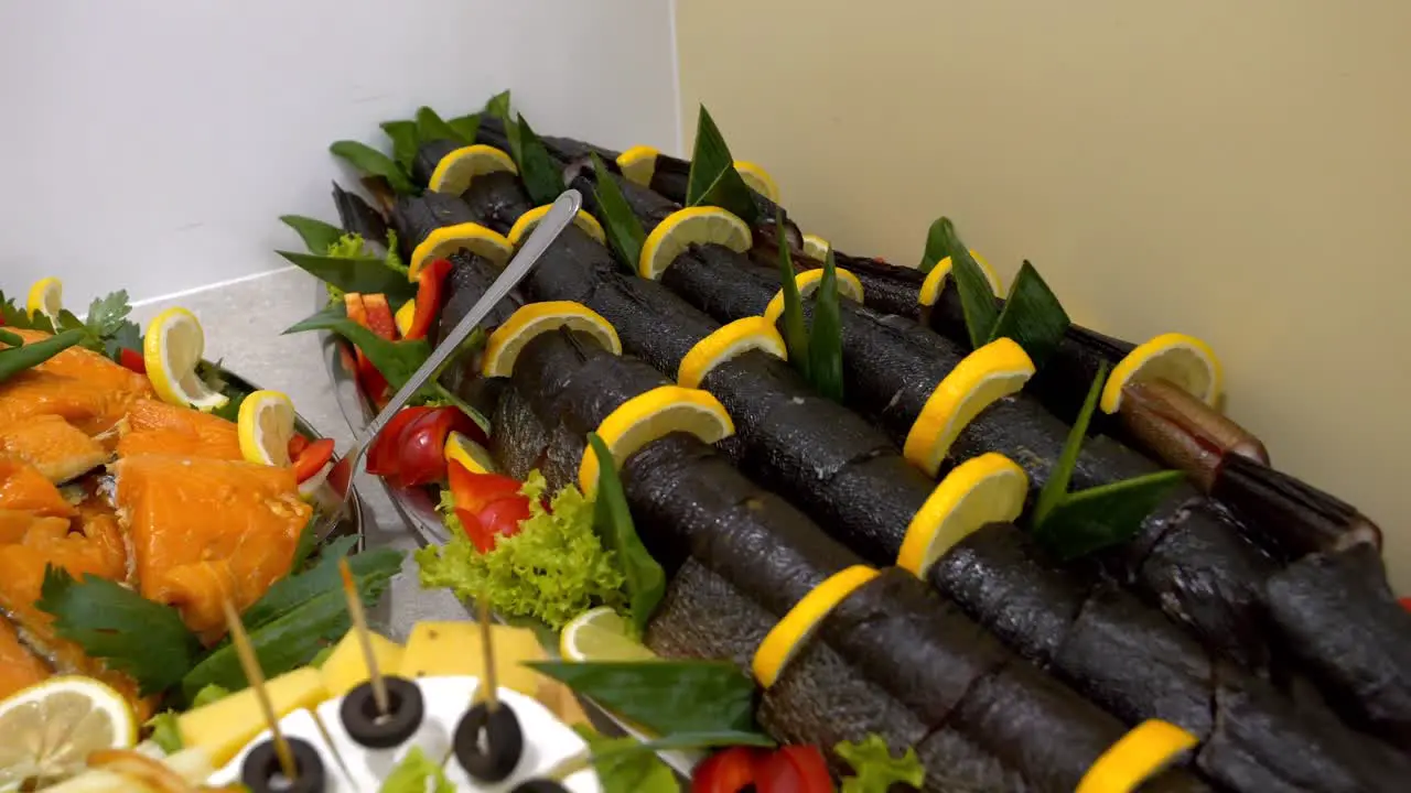 Platter with large pieces of smoked fish adorned with slices of lemon and orange