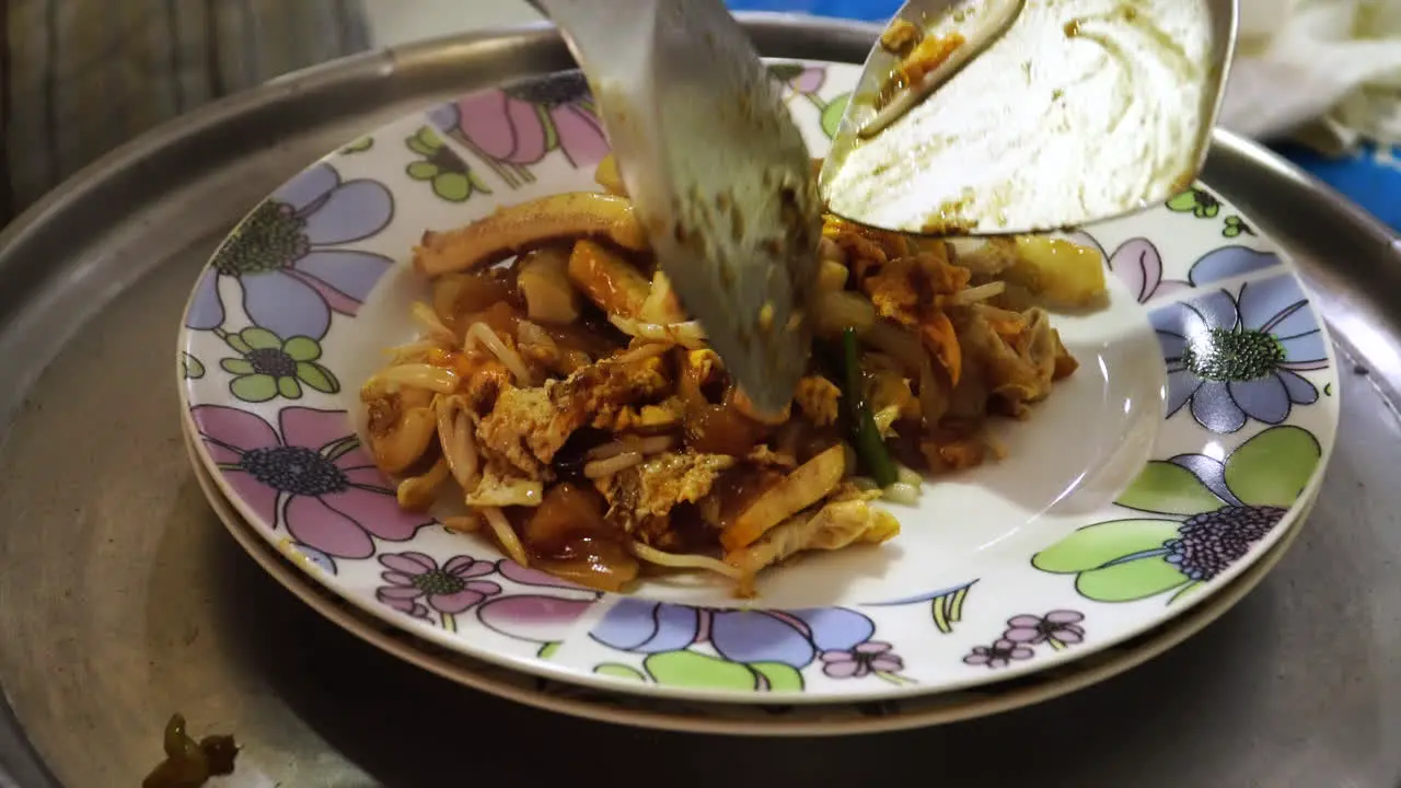 Thai seafood Pad Thai dish being dished up on plate close up view