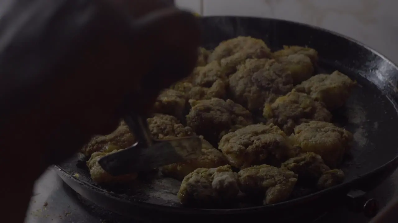 indian women hand flipping fried rawa prawns in black hot pan oil