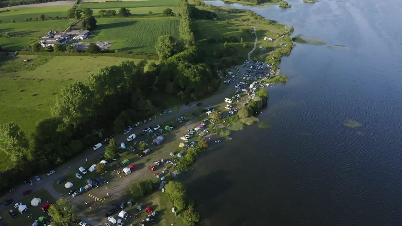 Sunny Family Camping Aerial Video of a Full Lakeside Campsite during a Summer Getaway