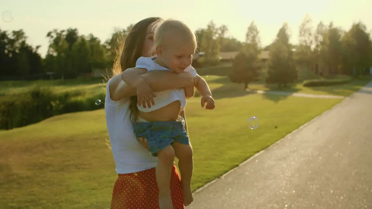 Mother holding little son on hands in park