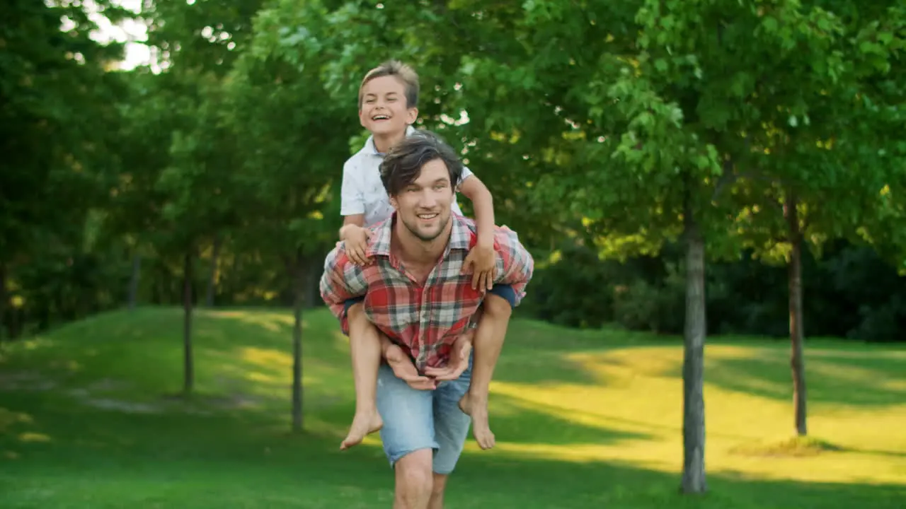 Boy jumping on father back in field