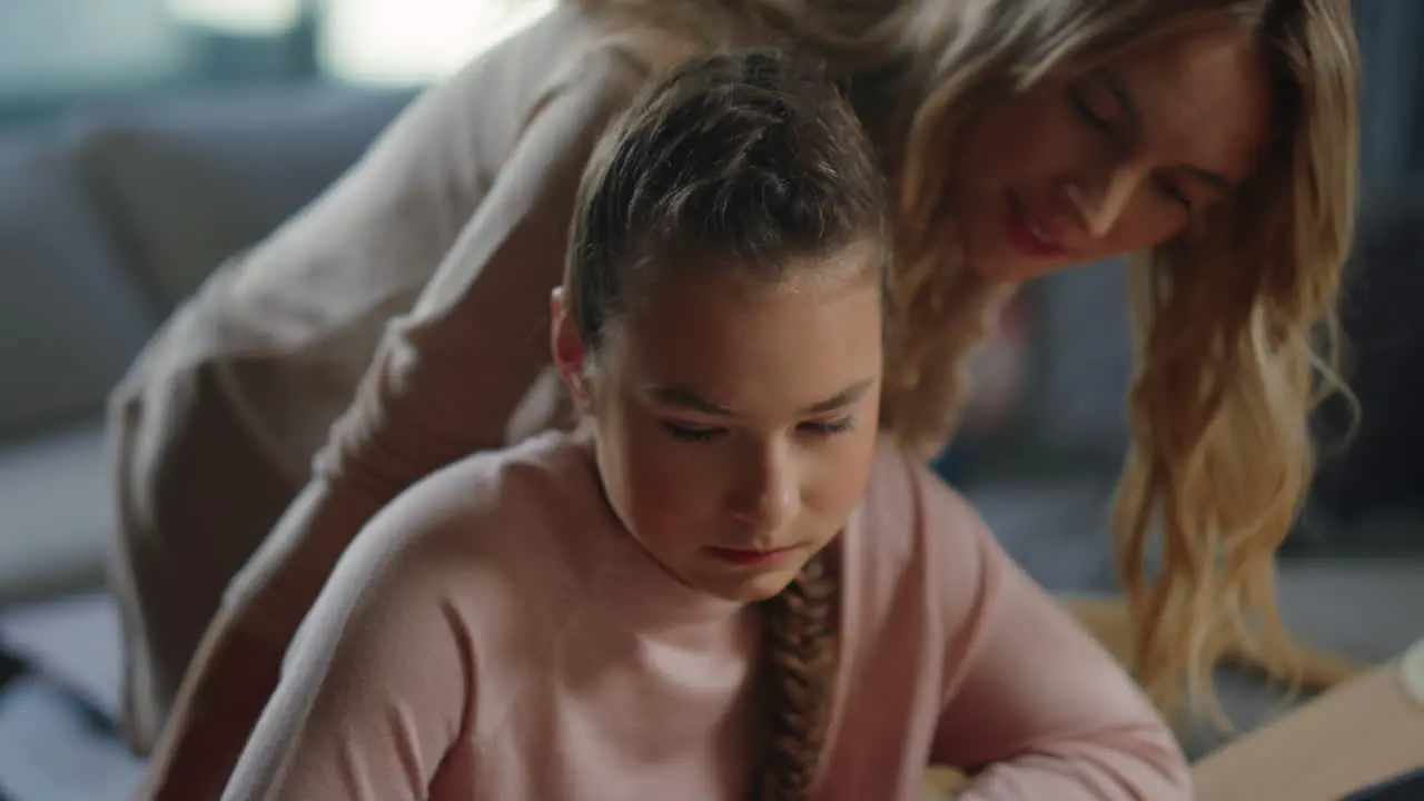 Daughter doing homework next to mom