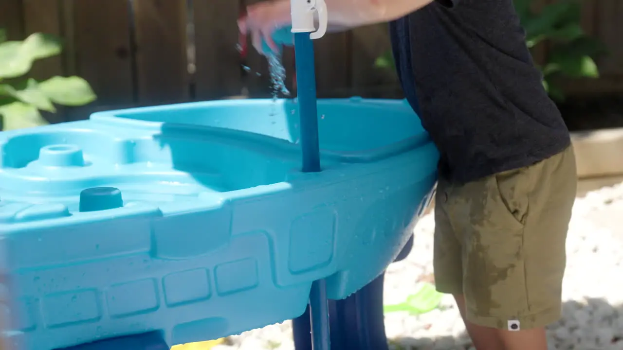 A kid splashing a toy boat in the water