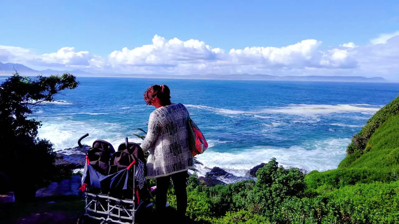 Mother interacts with twins in stroller whilst looking out over beautiful Walker Bay in Hermanus