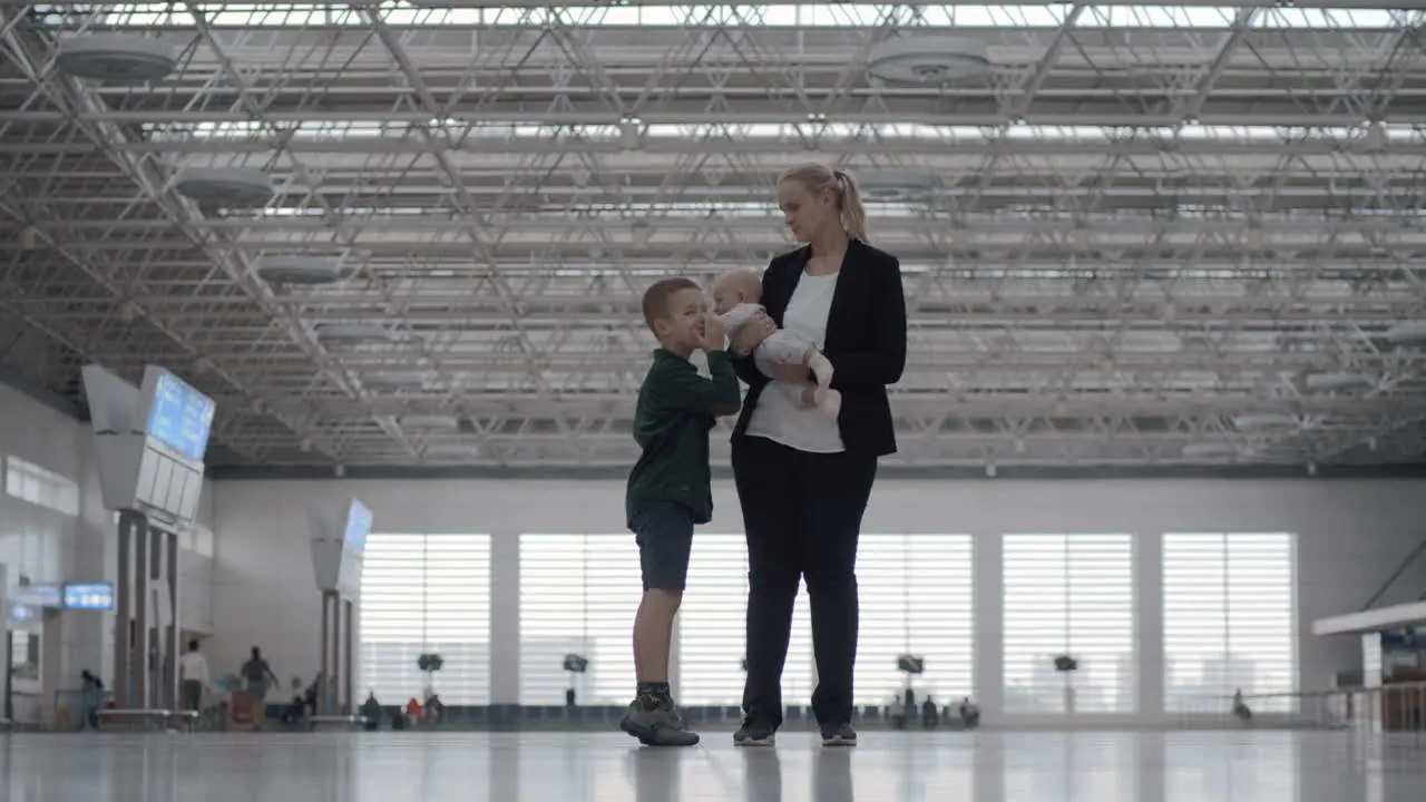 A woman with a baby daughter and a son in an airport hall