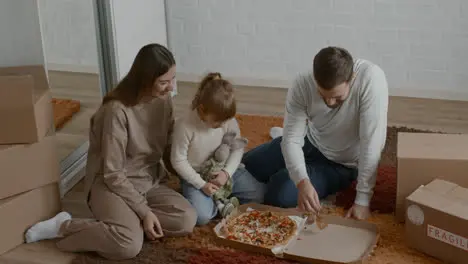 Family eating pizza on the floor