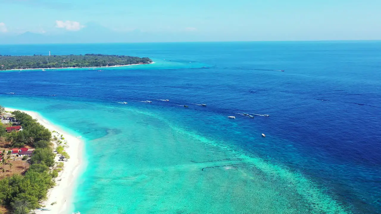 Blue turquoise sea full of boats floating surrounding shore of tropical islands with white beach and holiday hotels nearby in Indonesia