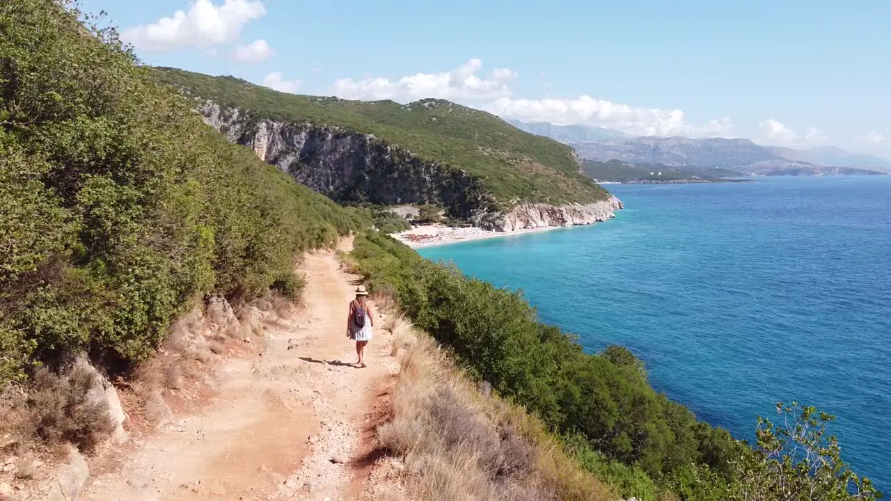 Tourist Girl walks to Beautiful Gjipe Beach in Albania Aerial Dolly Follow