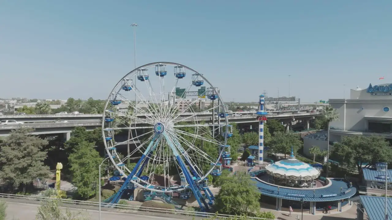 An aerial establishing shot of The Downtown Aquarium featuring featuring the Diving Bell Ferris wheel Aquatic Carousel and Lighthouse Dive under blue skies in downtown Houston Texas