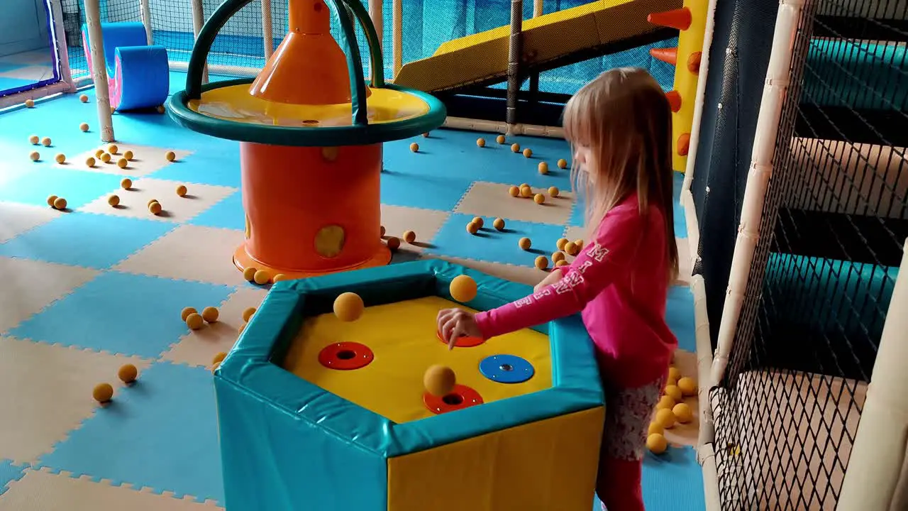 Cute 6 year old blonde girl in pink clothes playing and learning science with flying foam balls at indoor playground in Voss Norway Handheld static