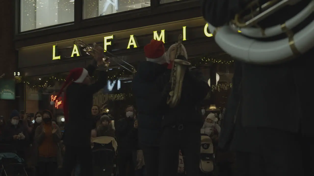 Street musicians dressed like Santa Claus plays on trumpets and saxophone