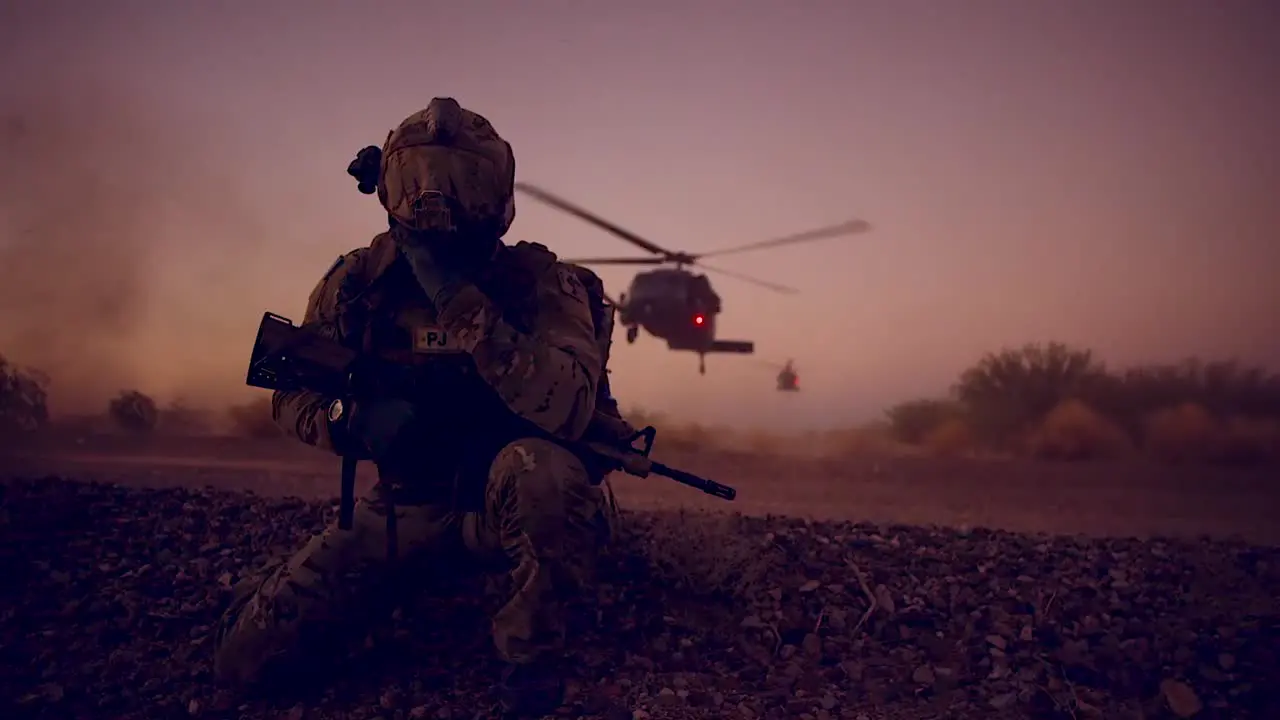 A Soldier Kneels As Helicopters Land On A Mission Behind Him